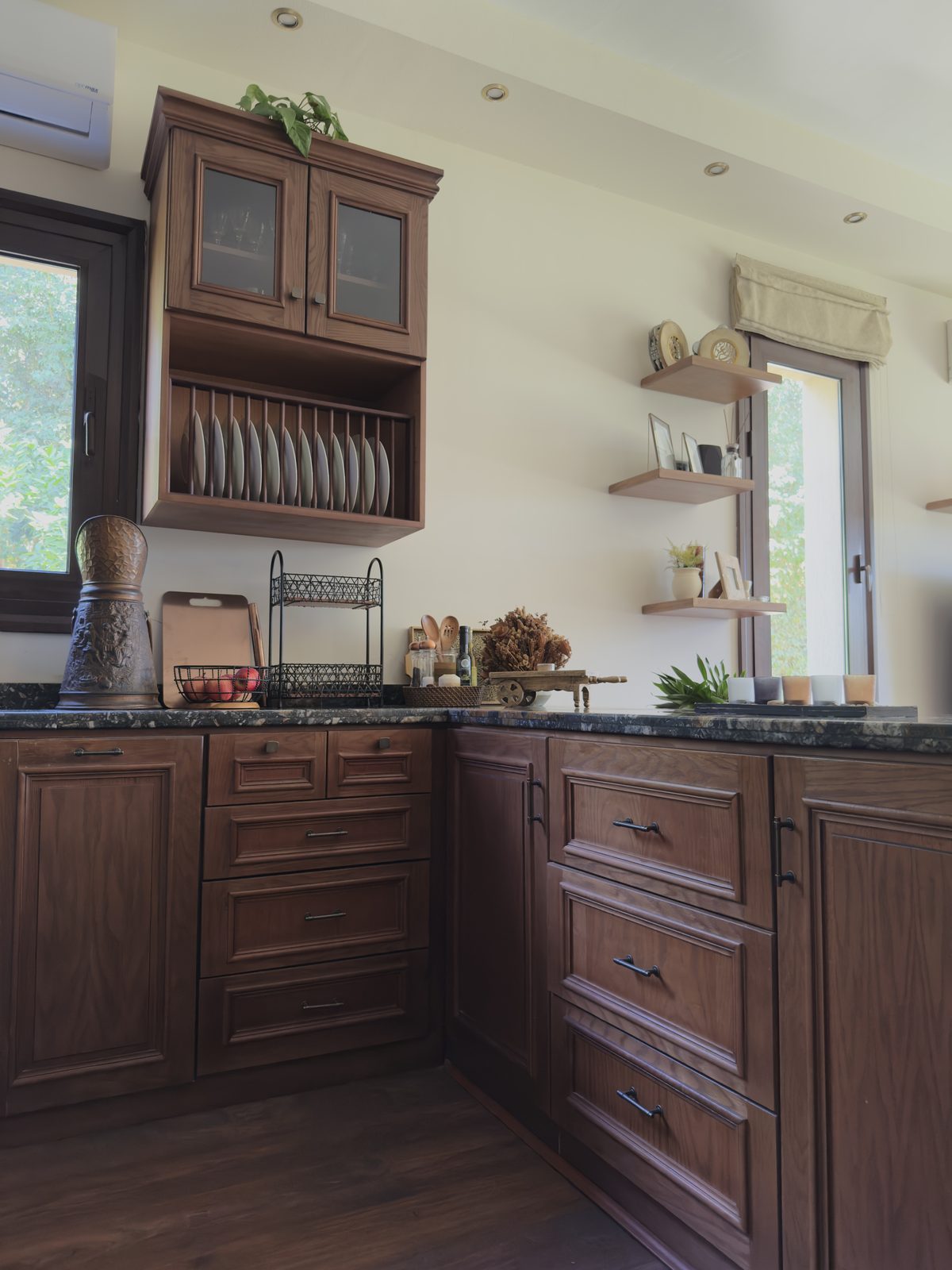 A built-in wooden plate rack above a fitted corner run of drawers in warm timber