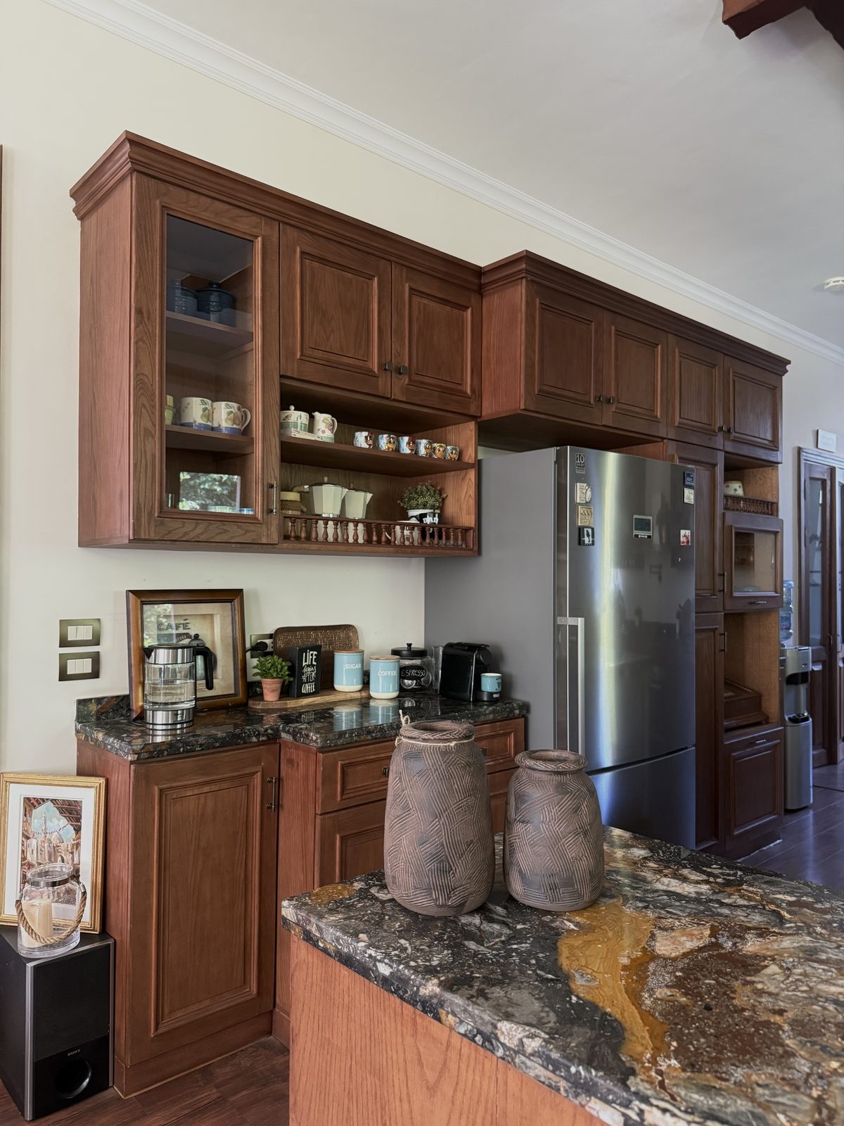 Glass-fronted display cabinets above dark granite in Dina’s own kitchen, the studio’s first build