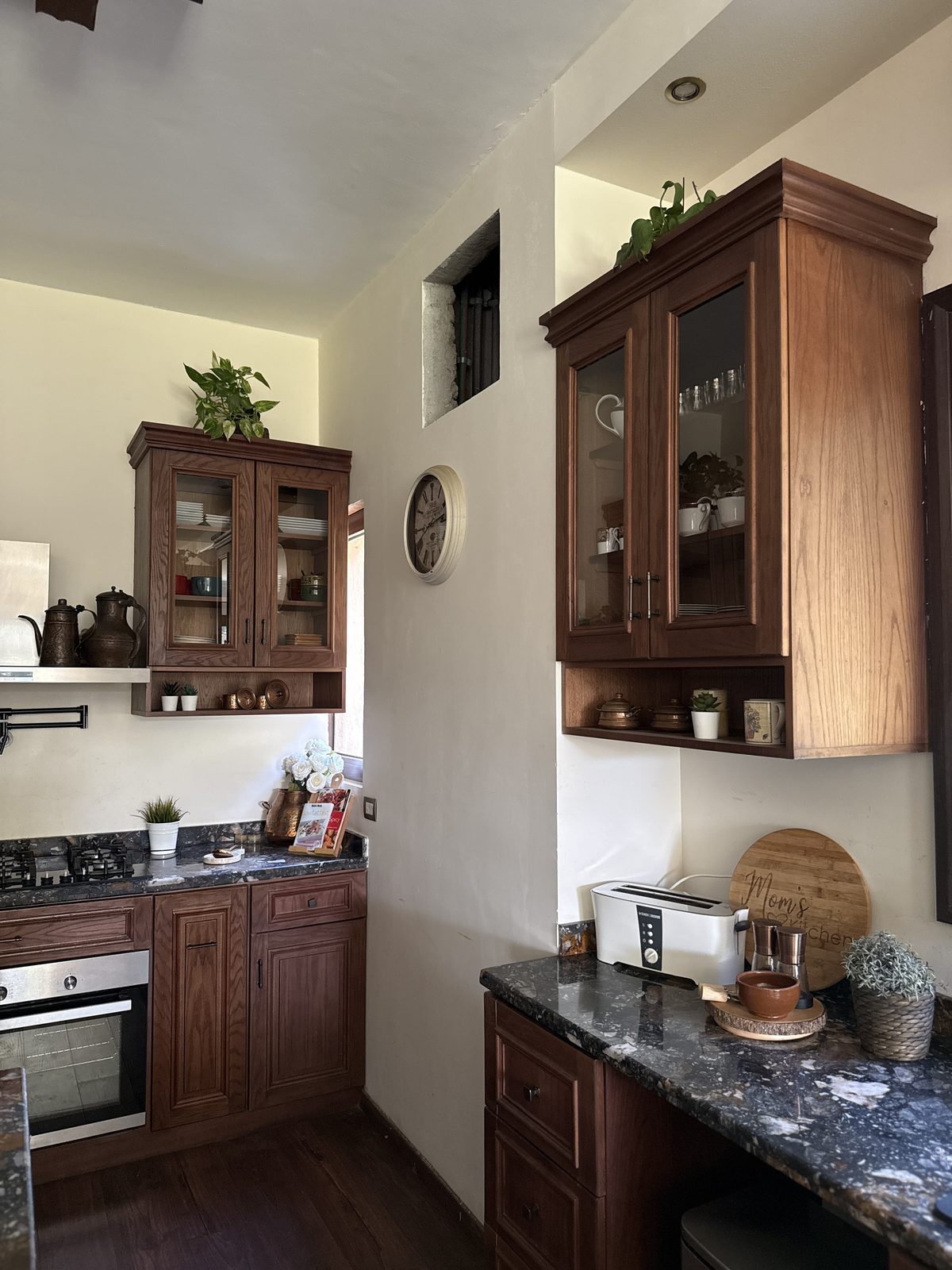 A breakfast corner with a wall clock, a glass-front cabinet and a toaster station in warm wood