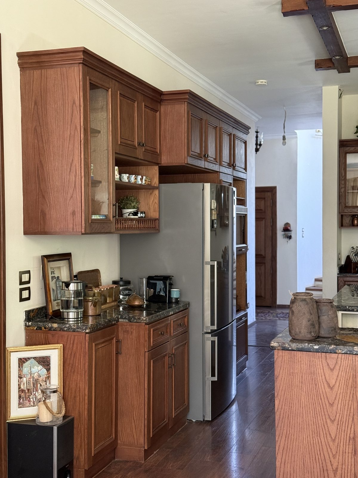 A coffee station beneath a glass display cabinet, opening through to the rest of the home